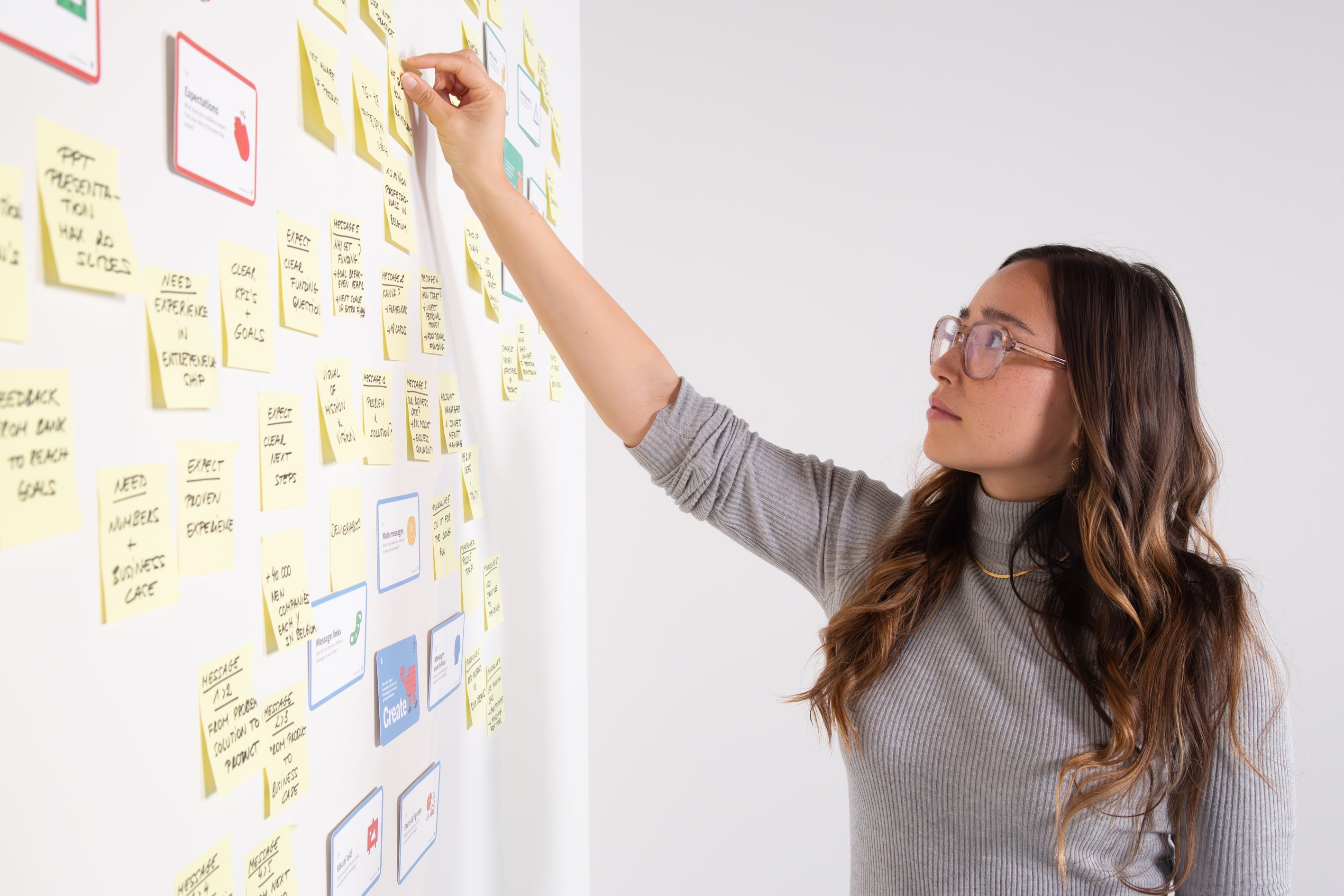 Founder organizing strategy cards and sticky notes on the wall